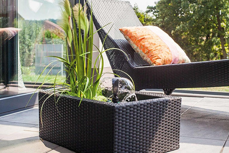 Garten mit Brunnen, Pflanzen und Liegestuhl