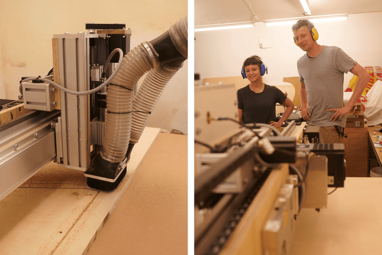 Computergesteuerte CNC-Fräsmaschine bei der Holzbearbeitung. Zwei Personen tragen Ohrenschützer.