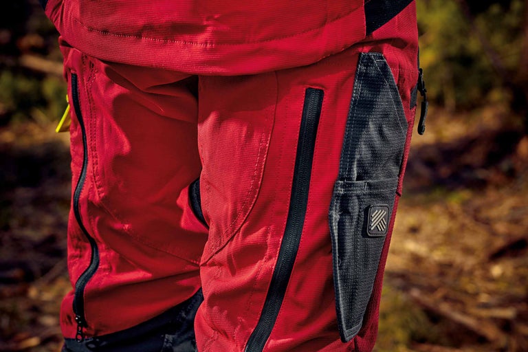 Detailaufnahme einer roten Arbeitshose mit Reißverschlusstasche und Werkzeugtasche