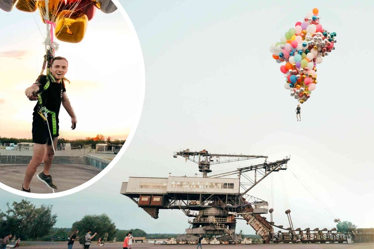 Mann fliegt mit Ballons vor einem Bagger