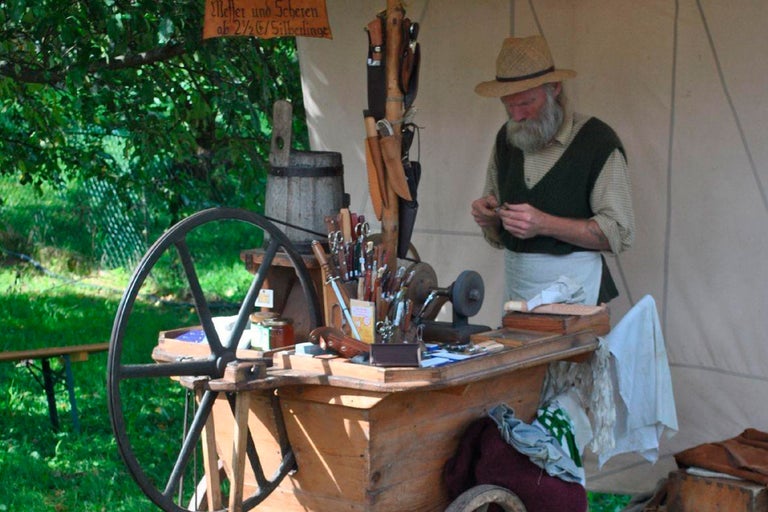 Handwerker an einem Marktstand mit Werkzeugen und Messern