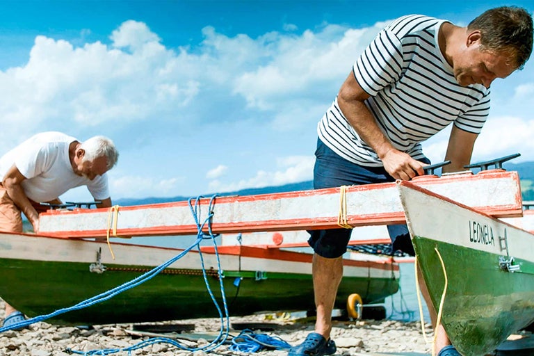 Zwei Männer bereiten Boote am Ufer für eine Fahrt vor.