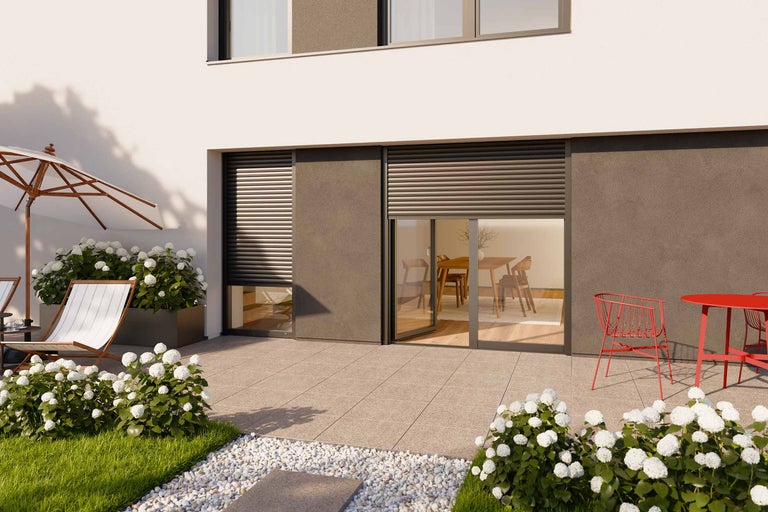 Terrasse mit Rollläden, Gartenmöbeln und Blumenbeeten