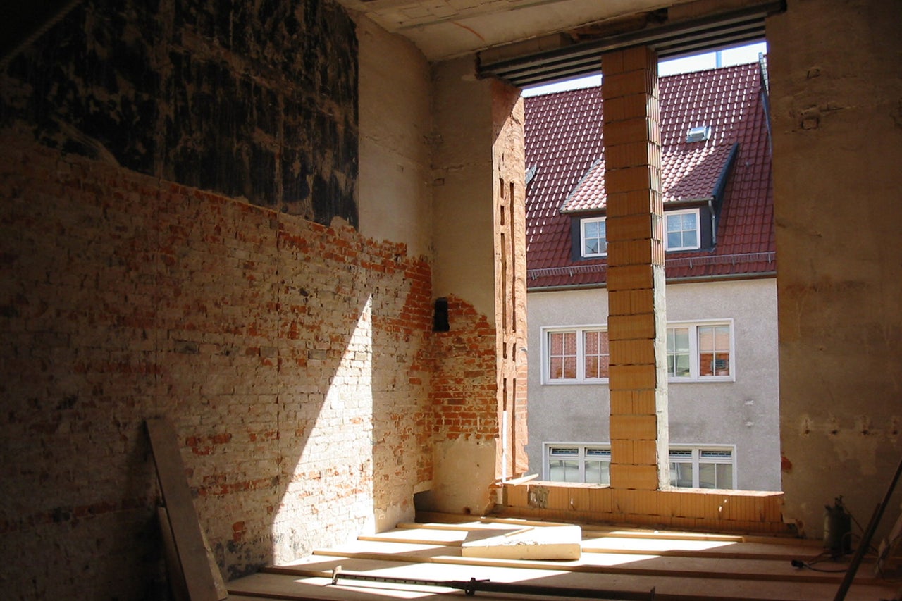 Innenraum eines Rohbaus mit Ziegelwand und Fensteröffnung