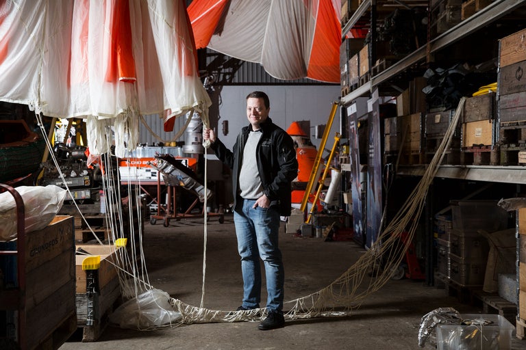 Mann steht in Lagerhalle mit Fallschirm