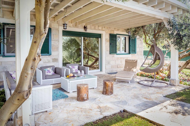 Terrasse mit Gartenmöbeln, Loungesesseln und Hängesessel unter einer Pergola