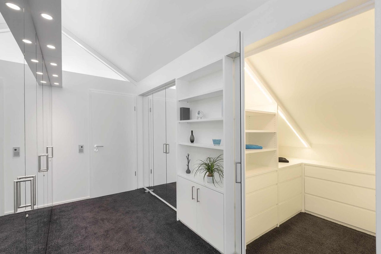 Heller Ankleideraum mit Schiebetürsystem und Regalelementen.
