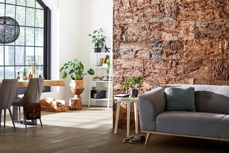 Heller Wohnraum mit Sofa, Tisch, Pflanzen und Wandpaneelen in Steinoptik