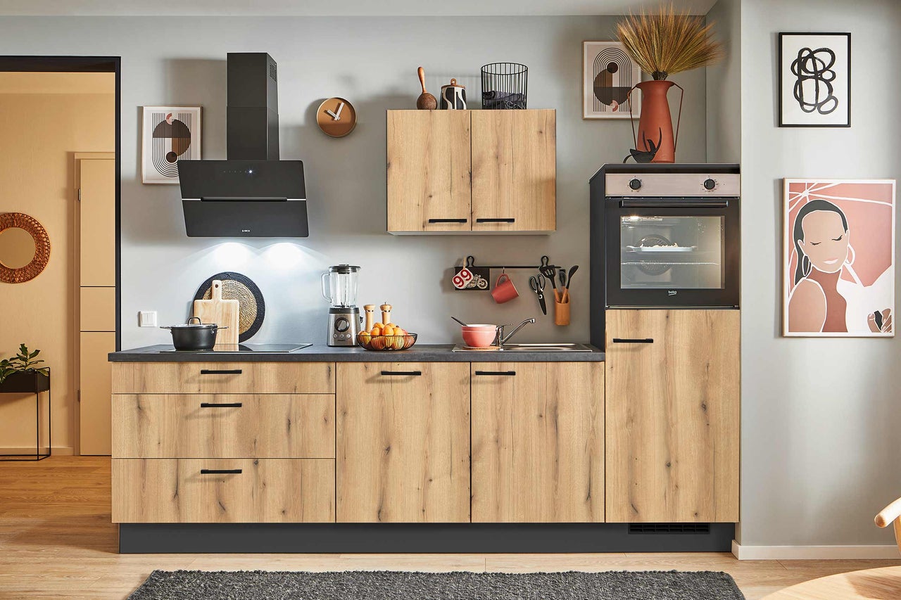 Moderne Küche mit Holzfronten, schwarzer Arbeitsplatte und verschiedenen Küchengeräten.