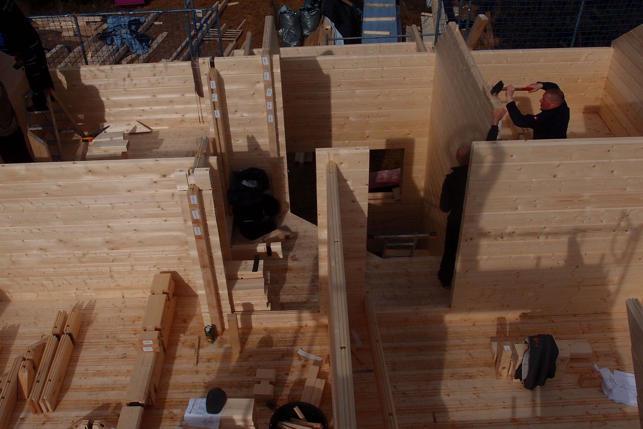 Aufbau eines Holzhauses mit Zimmerleuten, die Holzwände montieren