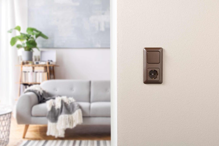 Braune Steckdose mit Schalter in einem Wohnraum
