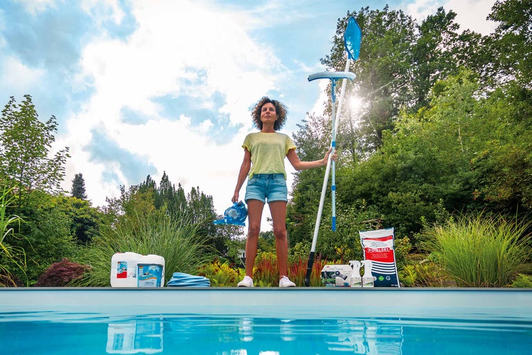 Frau mit Poolreinigungsset und Poolchemikalien am Pool