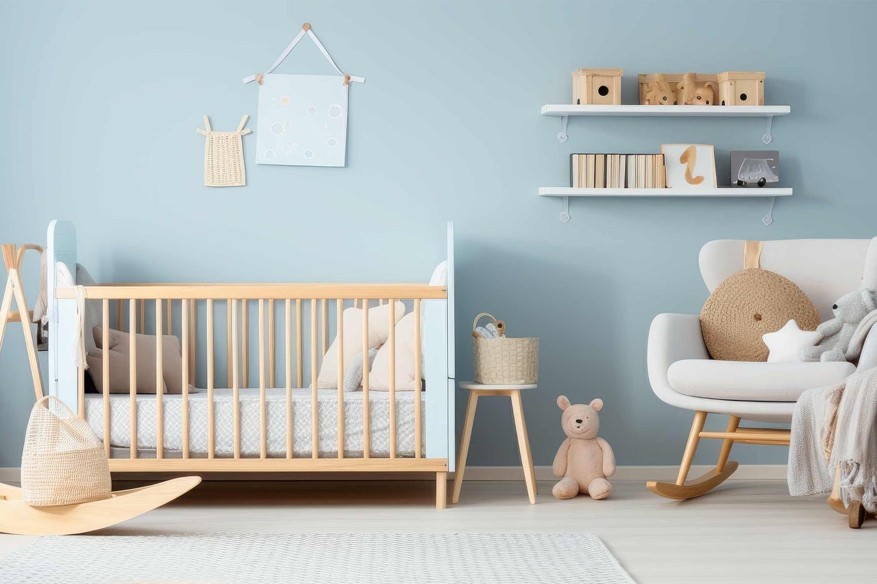 Hell eingerichtetes Kinderzimmer mit Babybett, Schaukelstuhl und Regalen