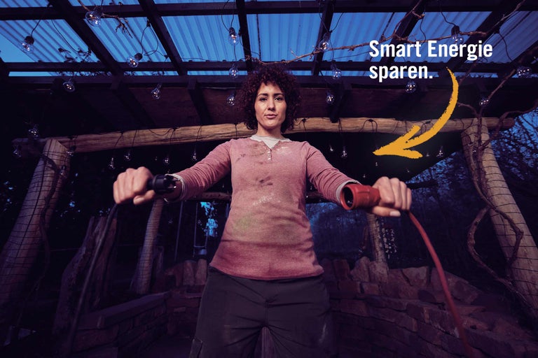 Frau hält eine Kabeltrommel in einem Garten mit Beleuchtung und dem Text Smart Energie sparen.