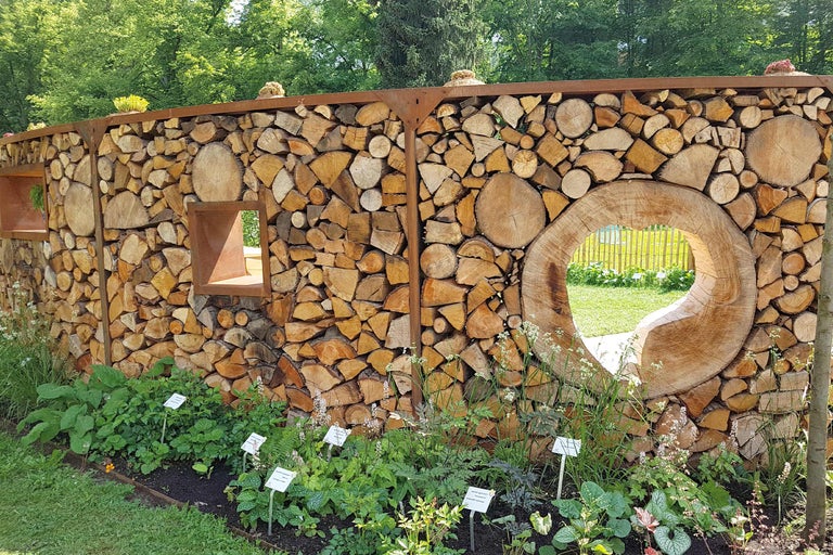 Dekorative Holzwand mit Öffnungen und Bepflanzung im Garten