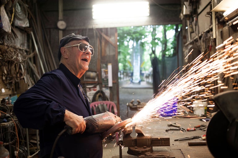 Ein Mann arbeitet mit einem Winkelschleifer in einer Werkstatt, wobei Funken sprühen.