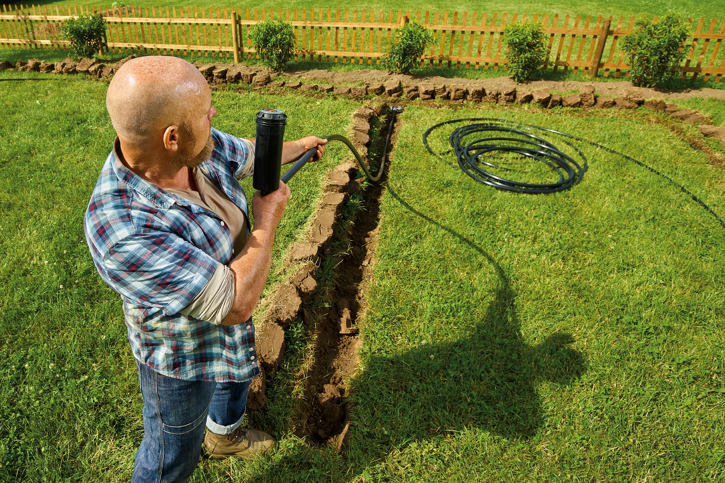 Ein Mann verlegt ein Bewässerungssystem in einem Garten