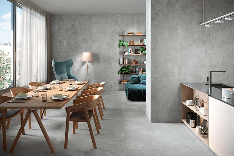 Innenraum mit Esstisch, Stühlen, Regalen und grauem Steinzeugfliesenboden.