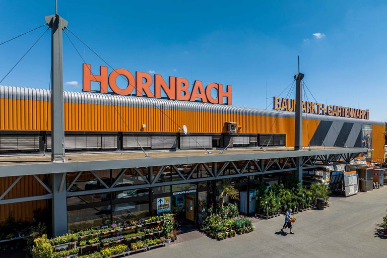 Außenansicht eines Hornbach Baumarktes mit Eingangsbereich und Pflanzenauswahl.