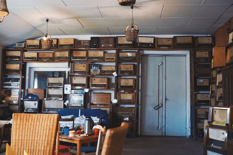 Innenraum mit Regalen voller alter Radios, Tisch und Stühlen
