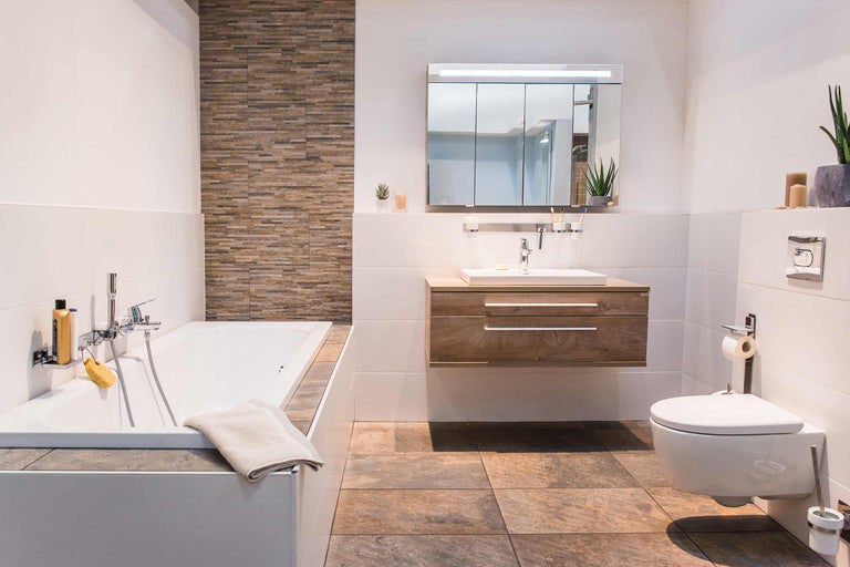 Modernes Badezimmer mit Badewanne, Waschtisch, Spiegelschrank und Toilette für eine helle und freundliche Atmosphäre