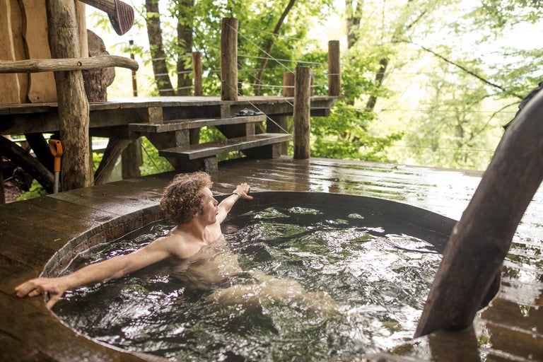 Mann entspannt im Badezuber mit Holzboden im Freien.