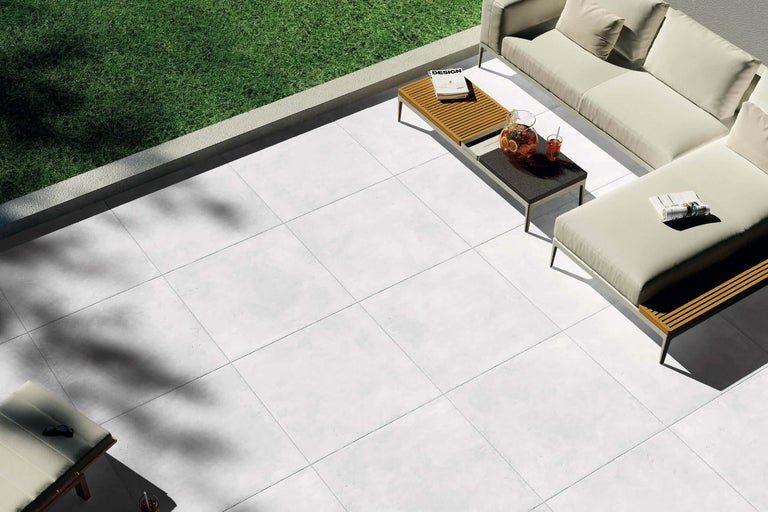Terrasse mit hellen Fliesen und Gartenmöbeln