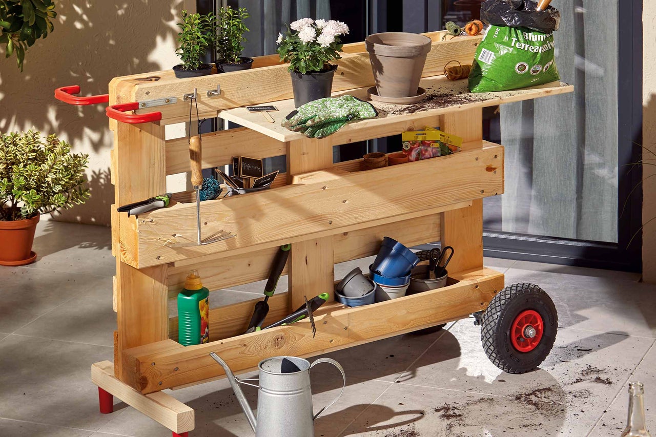 Gartenwagen aus Holz mit Gartengeräten, Blumen und Pflanzerde