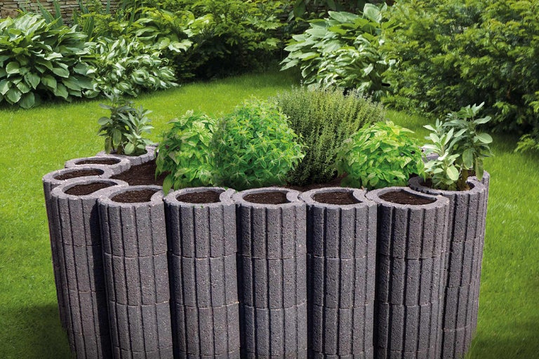 Blumenbeet aus Betonsteinen im Garten mit Kräutern bepflanzt