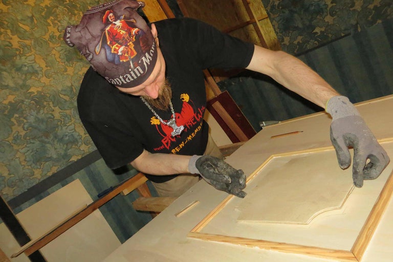 Ein Mann arbeitet an einem Holzrahmen mit Handschuhen