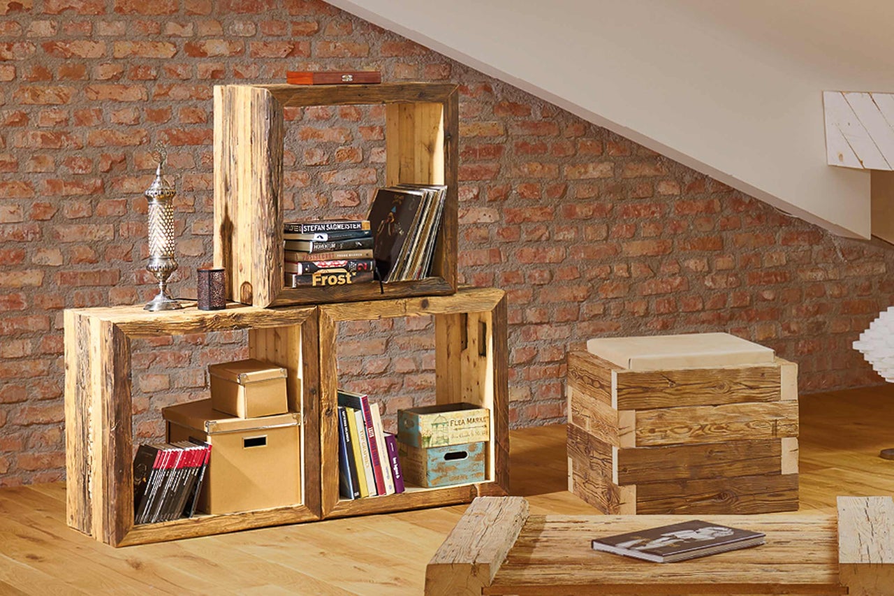 Regal aus Holz mit Dekoration vor einer Ziegelwand