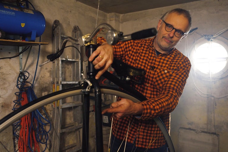 Mann repariert ein Fahrrad in einer Werkstatt.