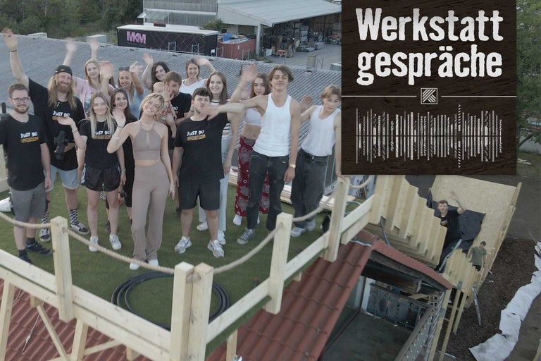 Eine Gruppe von Menschen steht auf einem Dach, im Hintergrund das Werkstattgespräche Logo