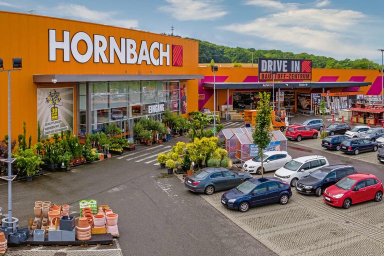 Hornbach Baumarkt Außenansicht mit Parkplatz, Pflanzen und Drive-In Baustoffzentrum.