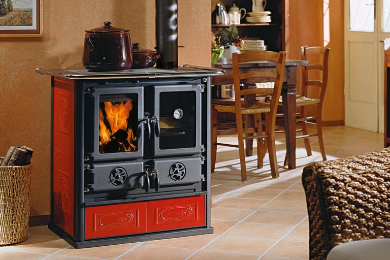 Holzofen mit Kochfunktion, Holzkorb und Kochtöpfen in einem Esszimmer.