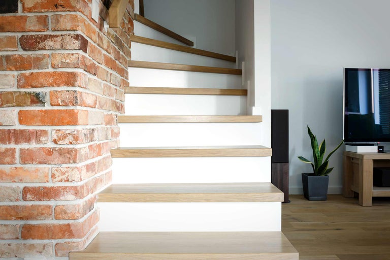 Treppe mit Holzstufen und Ziegelwand