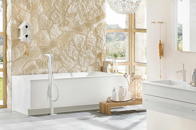 Badezimmer mit freistehender Badewanne, Waschtisch und Steinwand