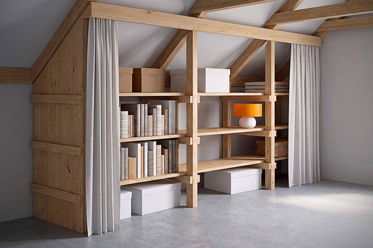 Holzregal mit Büchern, Kartons, Lampe und Vorhang in einem Dachzimmer