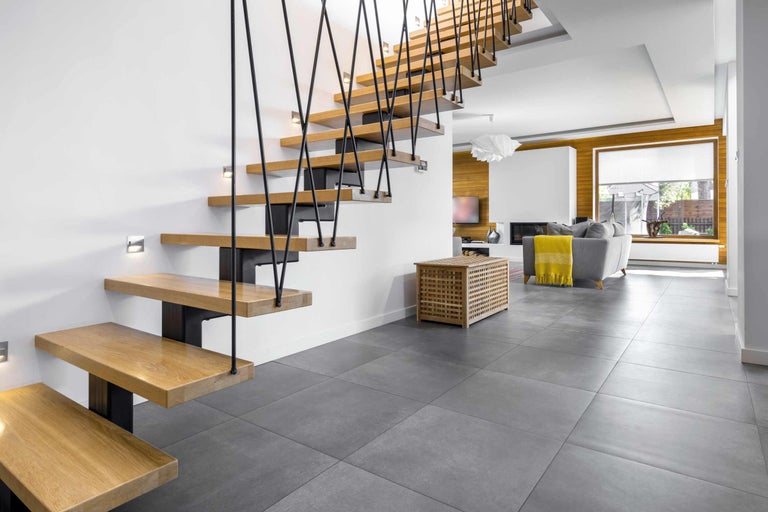 Helles Wohnzimmer mit Holztreppe, grauen Bodenfliesen und modernen Möbeln