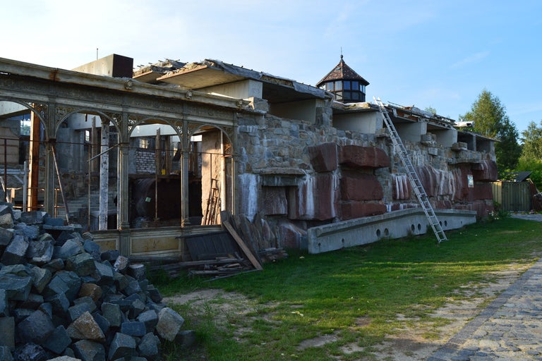 Rohbau eines Gebäudes mit Steinmauer und Leiter