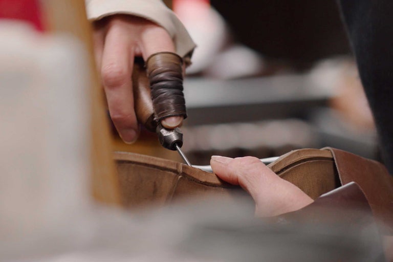 Eine Person benutzt eine Ahle zum Nähen von Leder