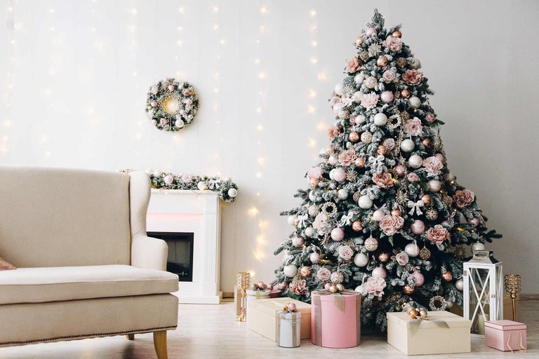 Dekorierter Weihnachtsbaum im Wohnzimmer mit Sessel, Kamin und Geschenken.