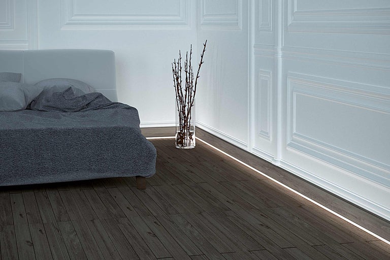 Schlafzimmer mit Bett, Vase und LED-Bodenleiste
