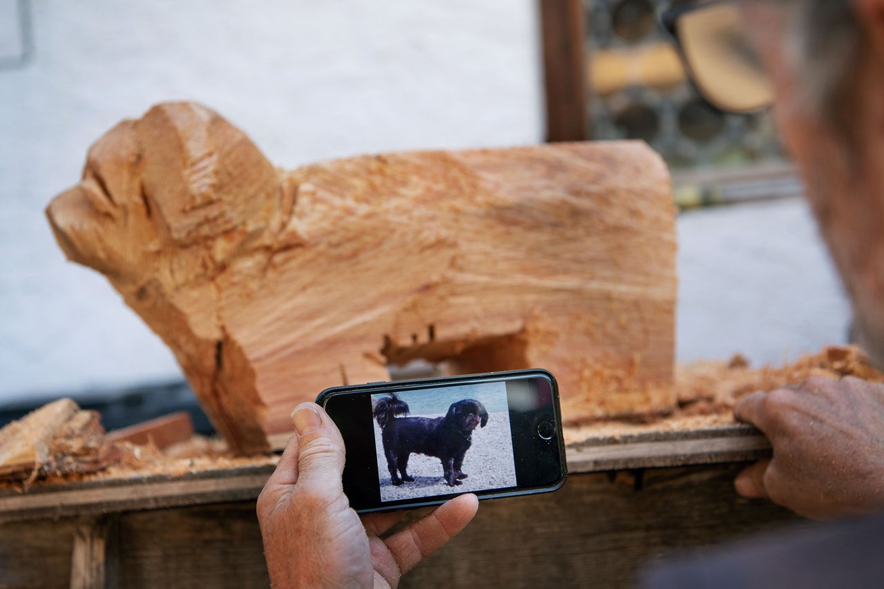 Holzrohling eines Hundes und ein Mobiltelefon mit einem Foto von einem Hund