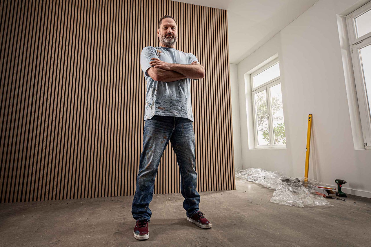 Raum mit Holzpaneelwand und stehendem Mann