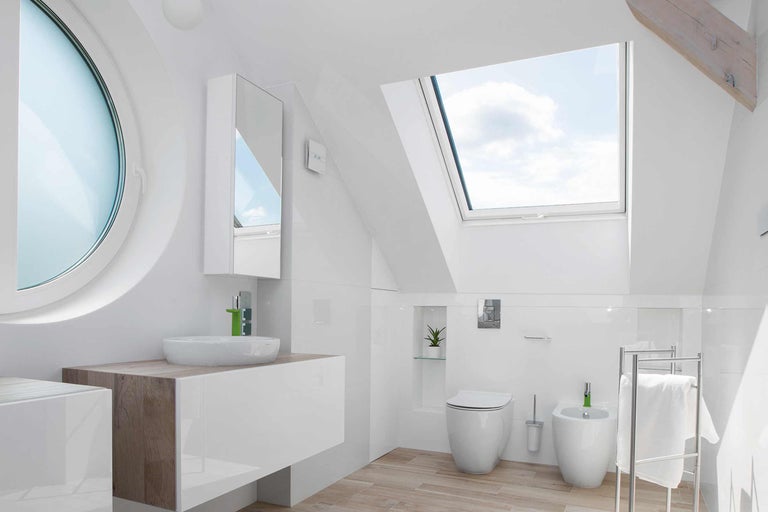 Helles Badezimmer mit Dachfenster, rundem Fenster, Waschbecken, Toilette und Bidet