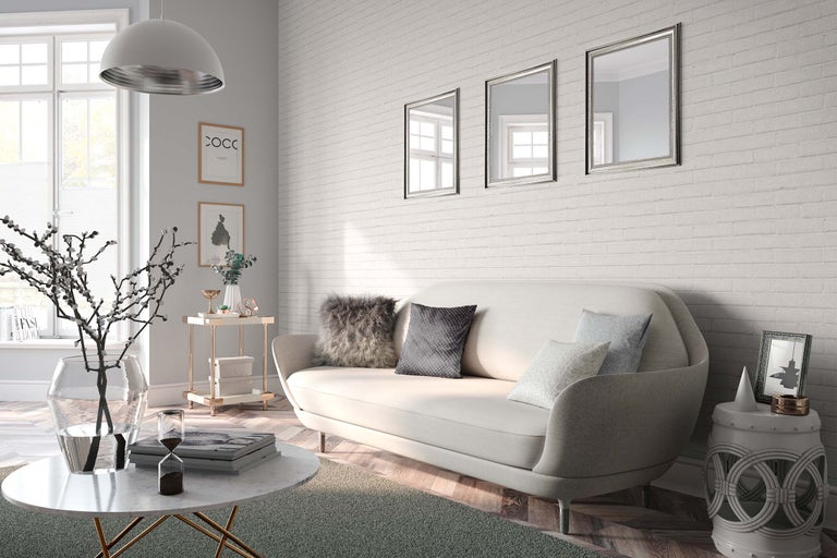 Helles Wohnzimmer mit Sofa, Couchtisch, Beistelltisch und Wanddekorationen vor einer Ziegelwand