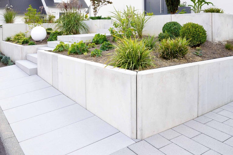 Gestalteter Garten mit Betonmauer und Bepflanzung