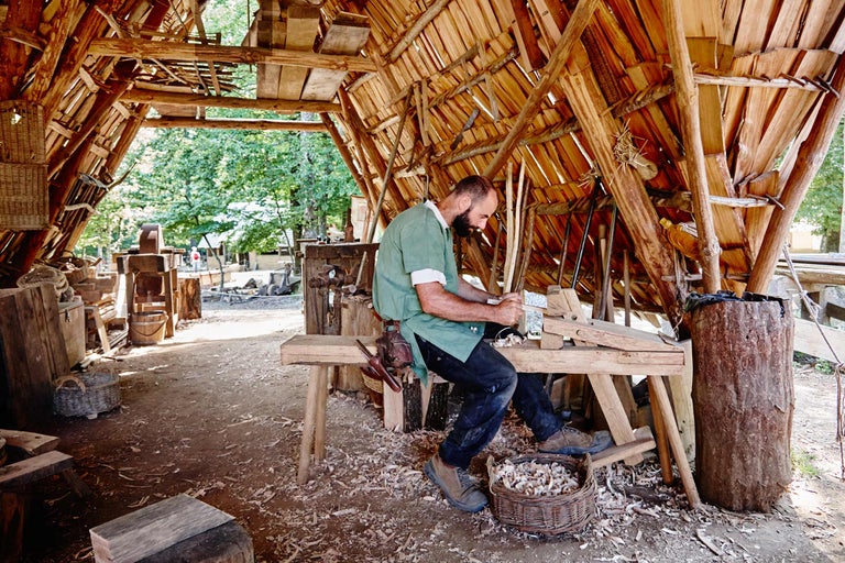 Ein Handwerker arbeitet in einer Holzwerkstatt mit Holzdach.