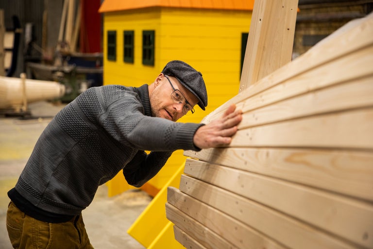 Mann begutachtet ein Holzspielhaus in einer Werkstatt.